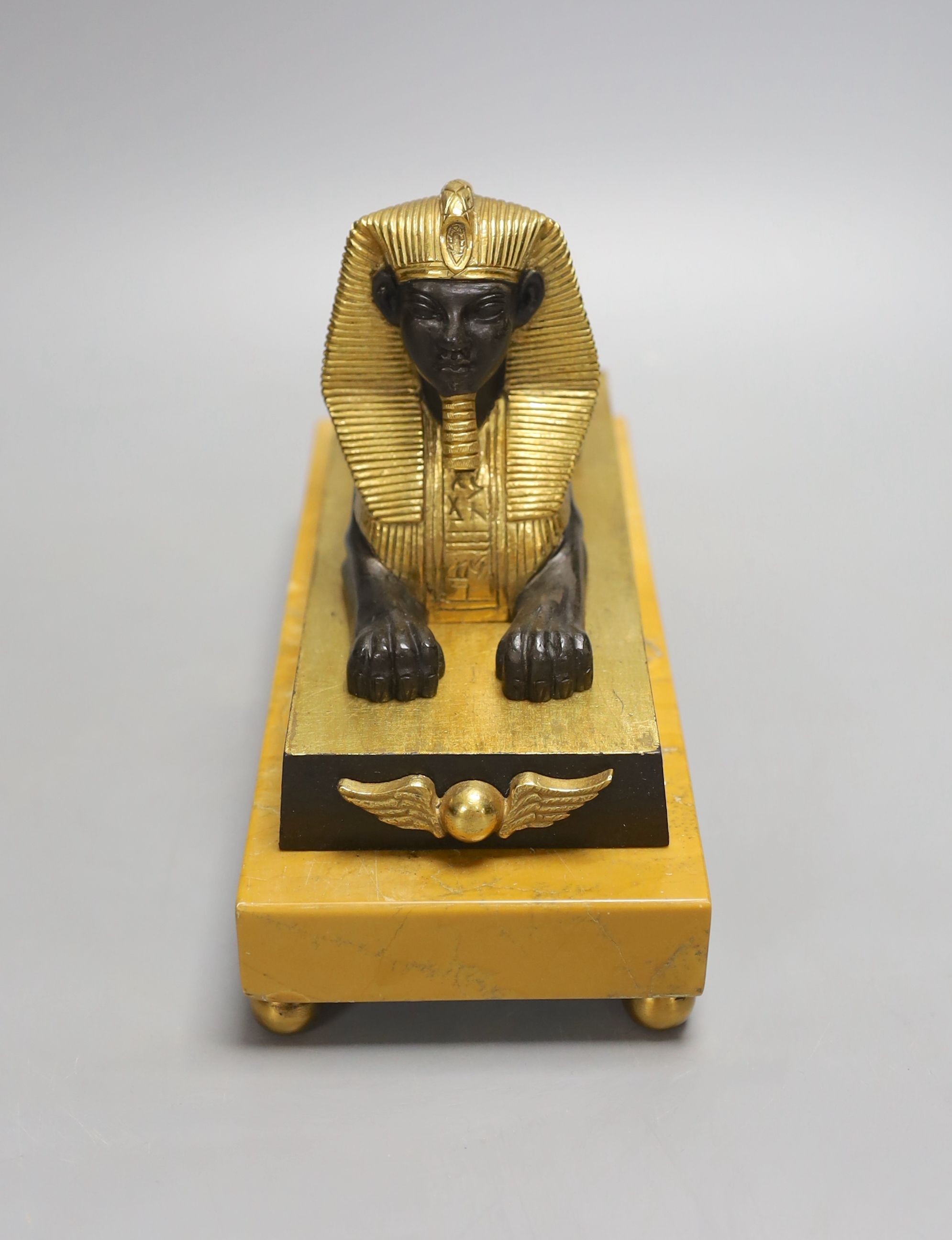 A parcel gilt bronze model of a sphinx on a Siena marble base - 22cm long